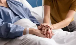 Wsparcie bliskiej osoby podczas leczenia paliatywnego. Dwie dłonie splatają się, symbolizując troskę i nadzieję.