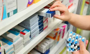 Ręka wybiera lek z aptecznej półki. Zastanawiasz się, po jakim czasie działa antybiotyk? To zależy od wielu czynników.