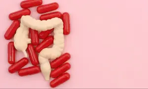 Model jelita otoczony czerwonymi kapsułkami. Może to symbolizować leczenie problemów z jelitami, jak np. preparaty asamax.