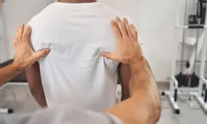 Fizjoterapeuta bada plecy pacjenta, sprawdzając, czy pierś może boleć od kręgosłupa.