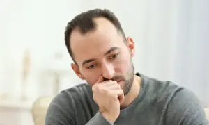Mężczyzna zamyślony, z ręką przy ustach. Może zastanawia się nad lekami, np. sertranorm.