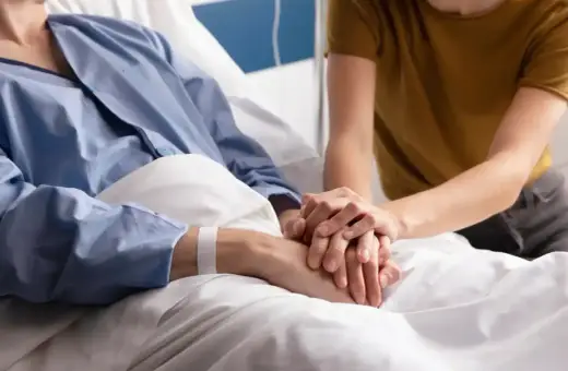 Wsparcie bliskiej osoby podczas leczenia paliatywnego. Dwie dłonie splatają się, symbolizując troskę i nadzieję.