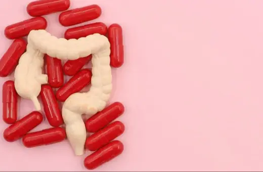 Model jelita otoczony czerwonymi kapsułkami. Może to symbolizować leczenie problemów z jelitami, jak np. preparaty asamax.