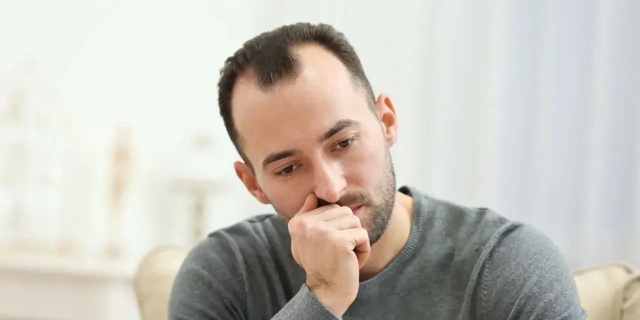 Mężczyzna zamyślony, z ręką przy ustach. Może zastanawia się nad lekami, np. sertranorm.