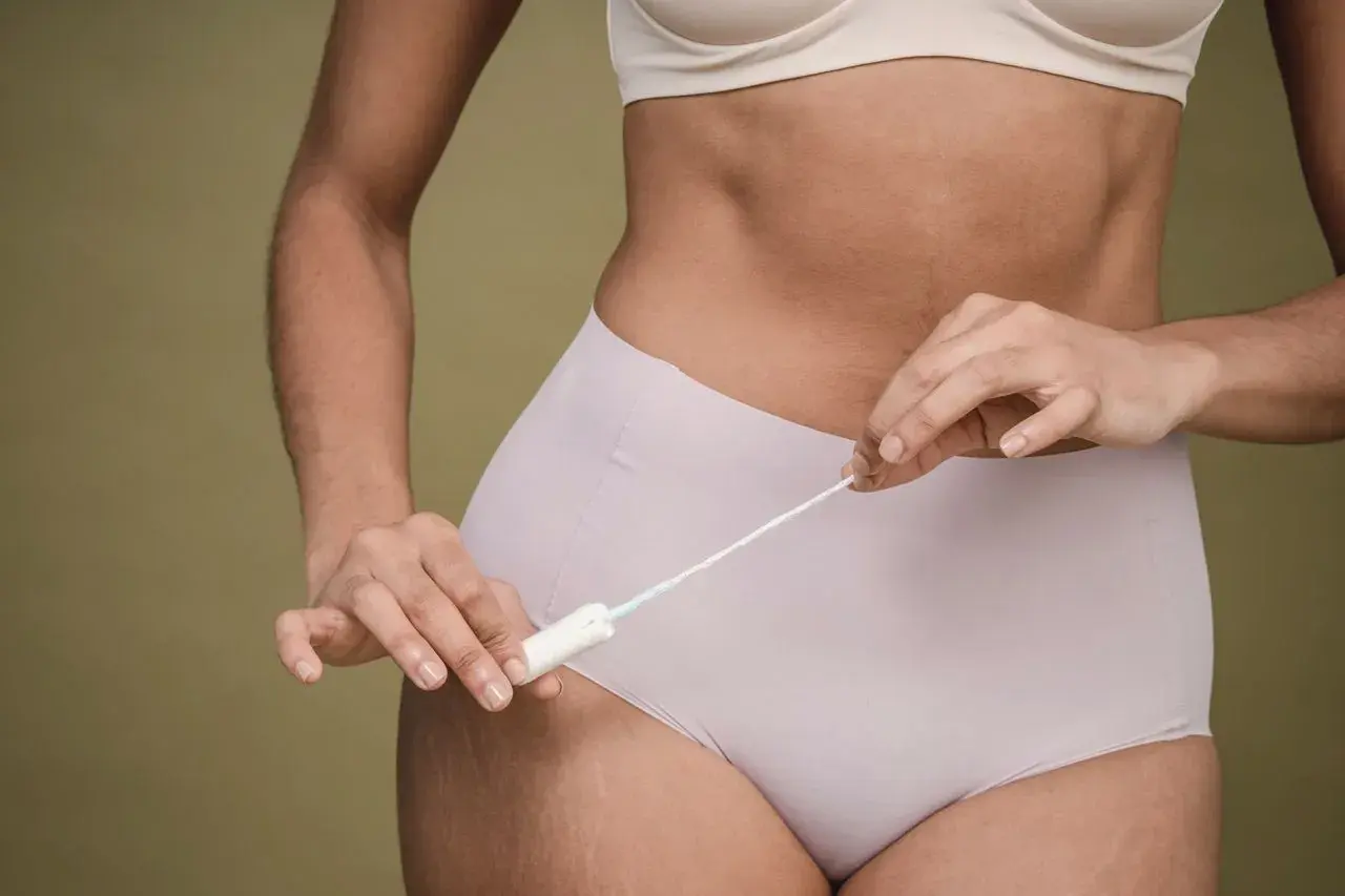 Kobieta trzymająca tampon, symbolizująca objawy miesiączki bez krwawienia.