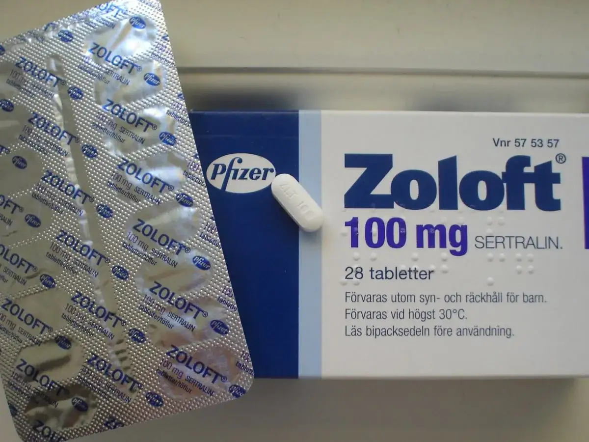 Opakowanie leku Zoloft z sertraliną, 100 mg, 28 tabletek. Obok blistry z tabletkami.